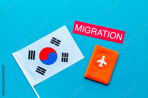 Migration to Korea concept. Korean flag near passport on blue background top-down