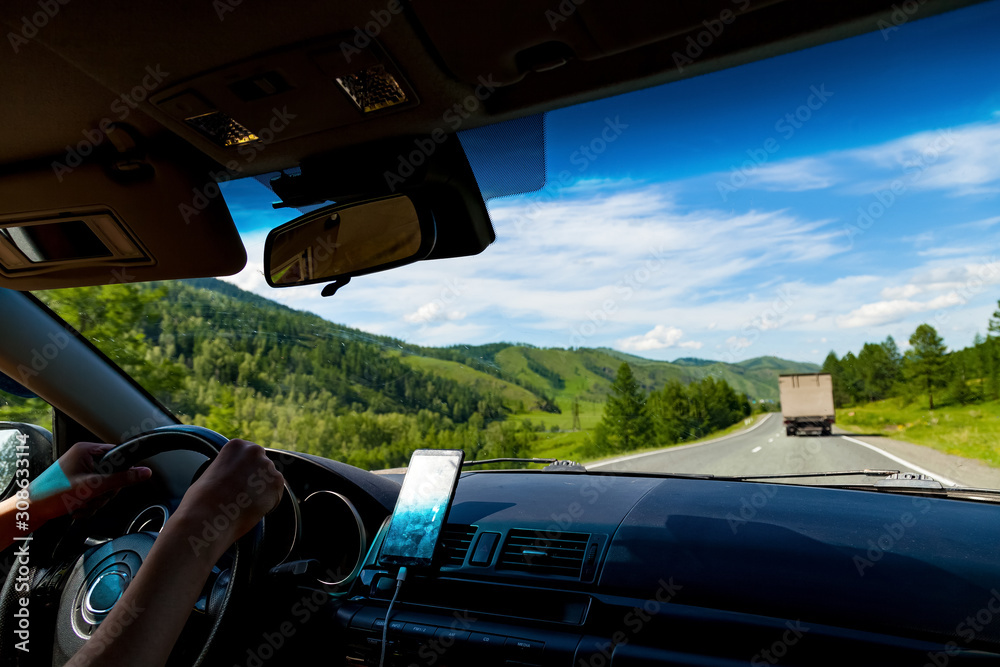 Family traveling by car in the mountains of the Altai are driving by serpentine road with navigation on the phone and view of picturesque places through the window.