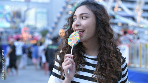 Holiday concept. Beautiful girls are eating lollipops happily in the amusement park. 4k Resolution.