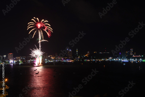 Pattaya International Fireworks Festival. Fireworks over cityscape by the beach and sea surrounding with Pattaya city alphabet in the night scene. 