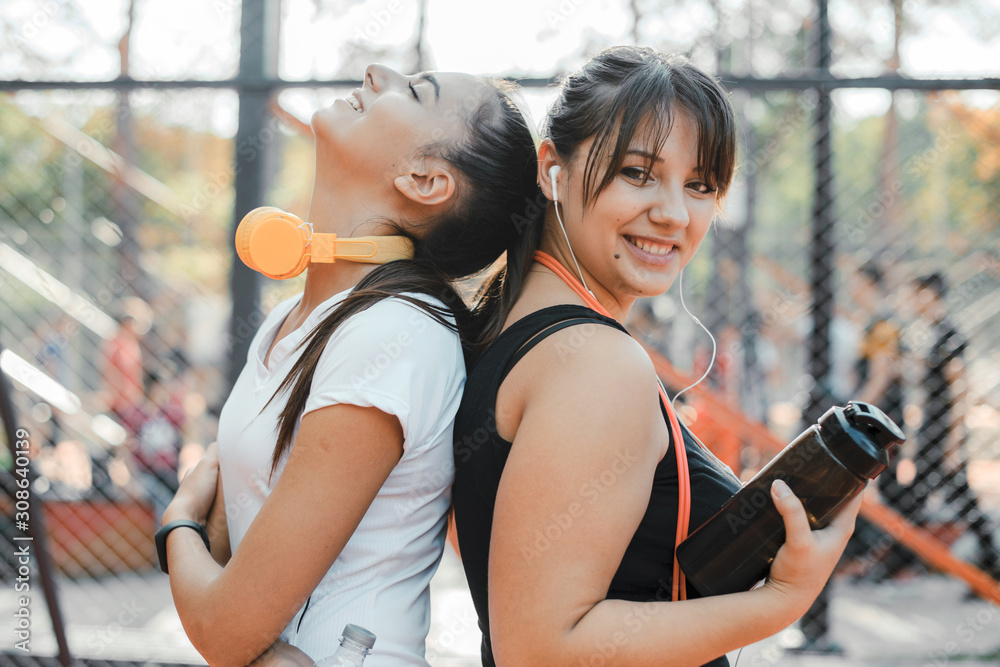 Portrait of two lovely woman looking at camera after doing exercise in the morning in a sport park for losing weight.