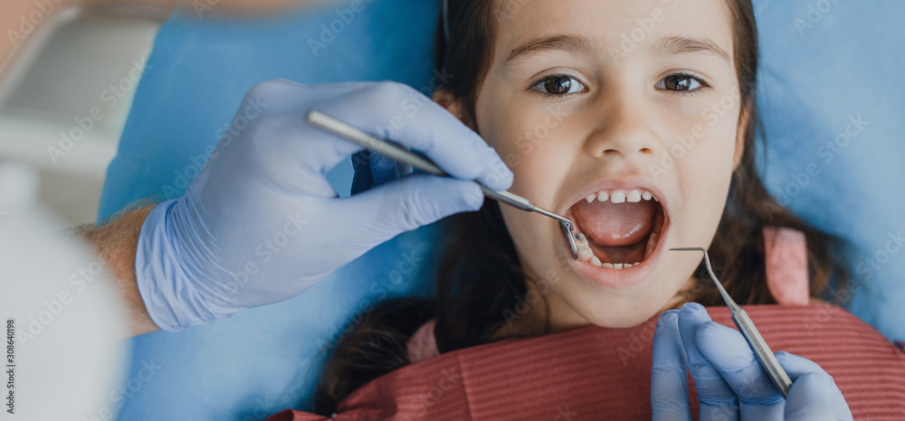Close up of a beautiful little girl siting in a stomatology seat having a tooth examination by a pediatric stomatologist. Close up of a beautiful little girl siting in a stomatology seat having a tooth examination by a pediatric stomatologist.