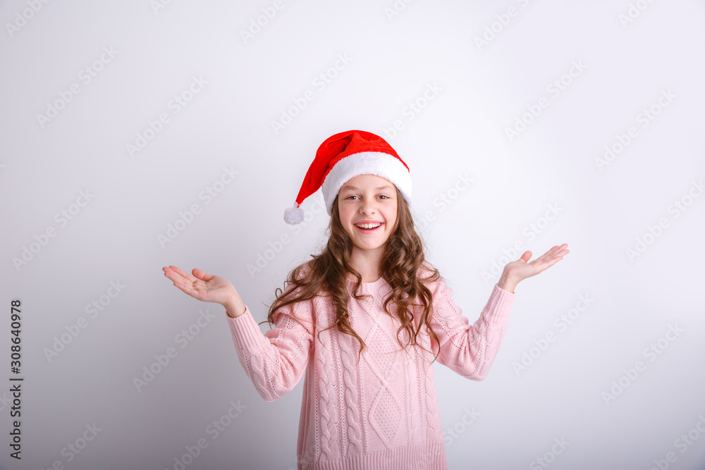 smiling little girl in Santa hat on isolated white background spread her arms to the sides shows surprise smiling little girl in Santa hat on isolated white background spread her arms to the sides shows surprise