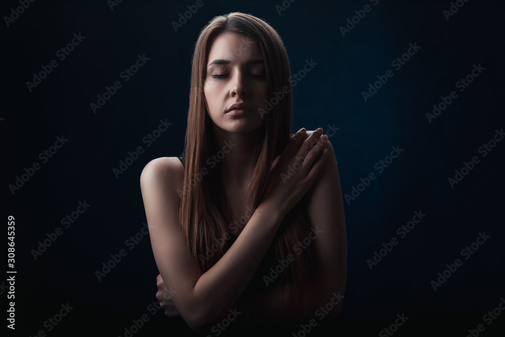 a girl with her eyes closed, hugged herself in the dark, the emotions of fear and cold a girl with her eyes closed, hugged herself in the dark, the emotions of fear and cold