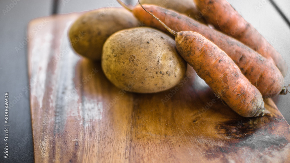 Potatoes and carrots crop on a wooden garden table background Potatoes and carrots crop on a wooden garden table background