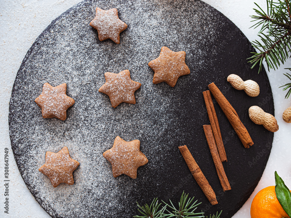 Homemade Christmas shortbread star shape sugar cookies with sugar powder, cinnamon, nuts, and cookie. Christmas baking. Overhead view. New year treat for Santa Claus cooking on a black board Homemade Homemade Christmas shortbread star shape sugar cookies with sugar powder, cinnamon, nuts, and cookie. Christmas baking. Overhead view. New year treat for Santa Claus cooking on a black board Homemade