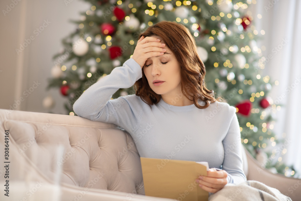 Young woman in grey shirt holding an envelope feeling upset Young woman in grey shirt holding an envelope feeling upset