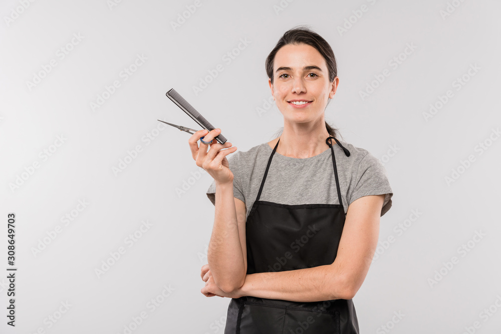 Pretty young professional female hairdresser with hairbrush and scissors Pretty young professional female hairdresser with hairbrush and scissors