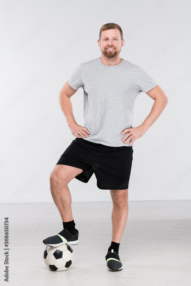 Young professional soccer player with foot on ball standing in front of camera