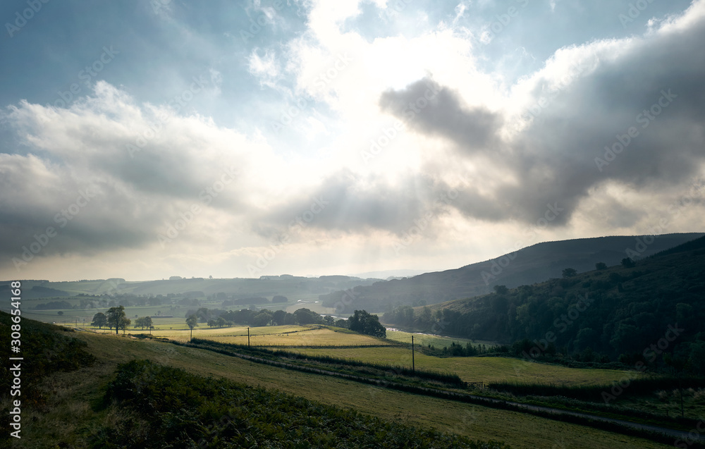 Bright Sunlight coming through clouds over Coquetdale countryside in Northumberland, North East England.