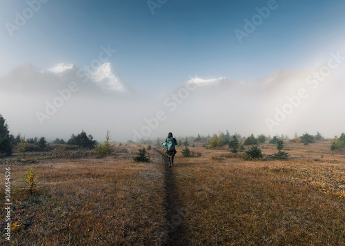 Man backpacker trekking on field with rocky mountains in foggy at provincial park