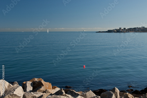 Single tall white sail cruises in blue waters in the Dun Laoghaire Ireland, Europe