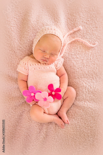 Portrait of a newborn sleeping baby with pink flowers. Birth concept