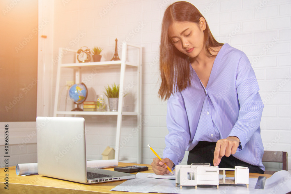A beautiful female engineer or beautiful female architect working in the office.