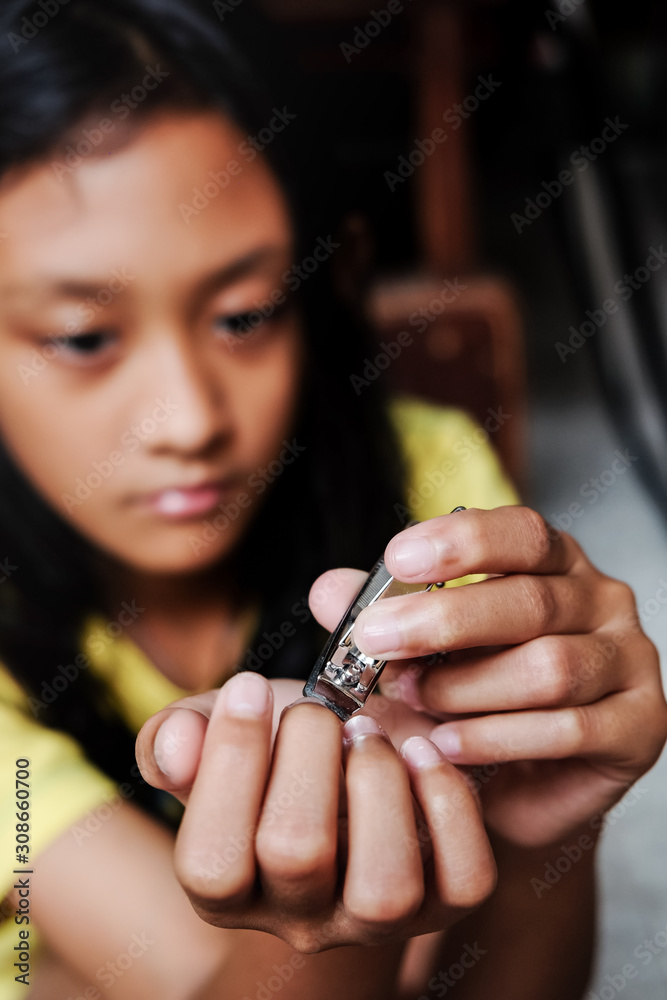 Closeup Portrait of Southeast Asian Ethnic Teenage Girl Cutting Her Fingernail Using Nail Clipper Closeup Portrait of Southeast Asian Ethnic Teenage Girl Cutting Her Fingernail Using Nail Clipper
