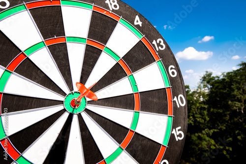 Dart arrow hit on bulleyes of dartboard with blue sky, Planning new business target and goals