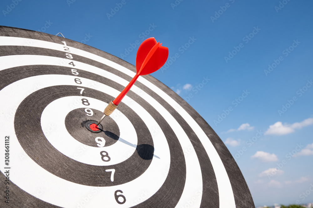 Dart arrow hit on bulleyes of dartboard with blue sky, Planning new business target and goals Dart arrow hit on bulleyes of dartboard with blue sky, Planning new business target and goals