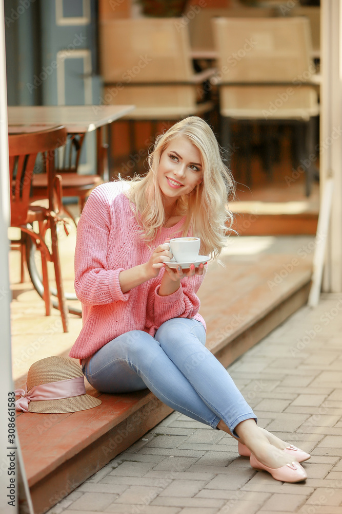 attractive woman in romantic mood smiling in happiness sitting at table wearing pink jacket, stylish apparel, waiting for boyfriend on a date in cafe, drinking cappuccino, exited face expression.