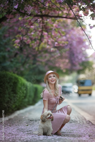 Cute adult girl with a small breed dog in pink clothes.