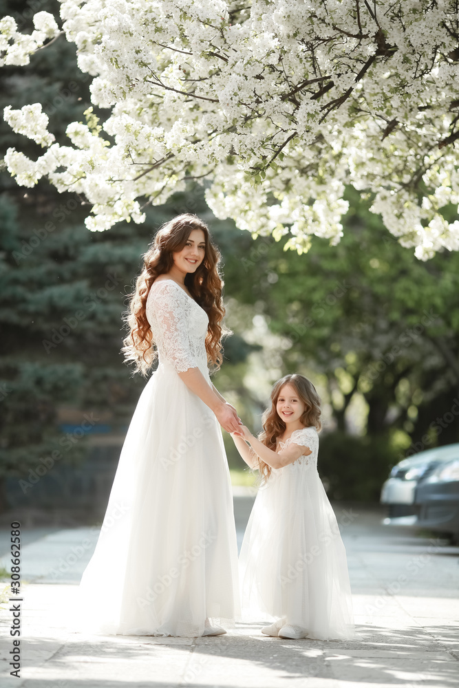 Mother dressed in a white dress as a bride walks in the Park with her daughter.