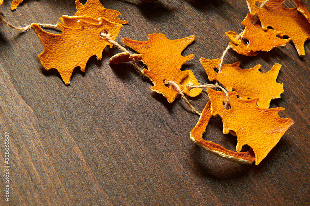 Obraz premium Christmas and new year holiday concept with copy space - handmade decoration from dried peel of oranges in a fir tree shape on a dark wood background
