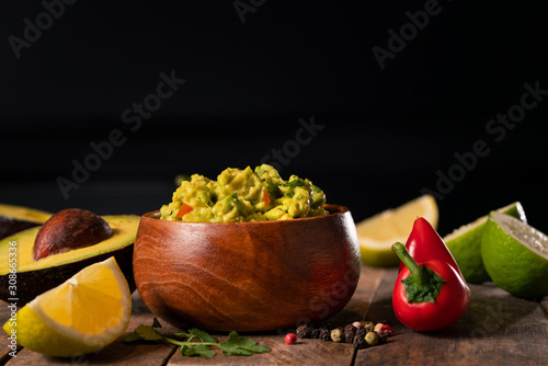 Spicy guacamole on black background rustic wooden surface