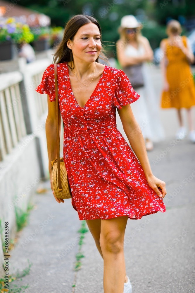 Young woman in red dress walking alone downtown
