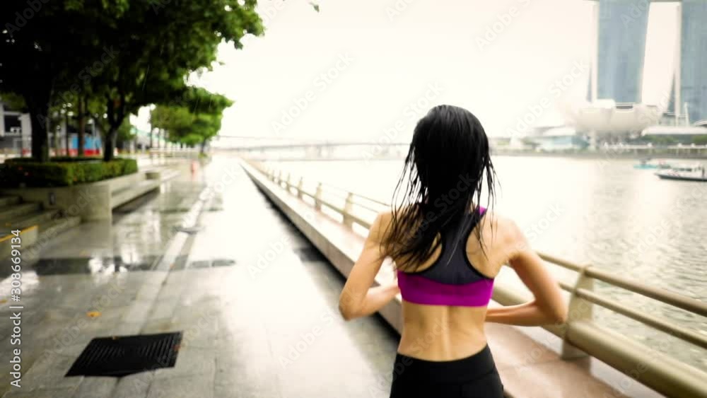Middle-aged Asian woman jogging in the rain in Singapore