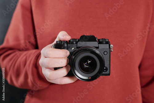 Hands of contemporary male photographer with new photocamera by chest