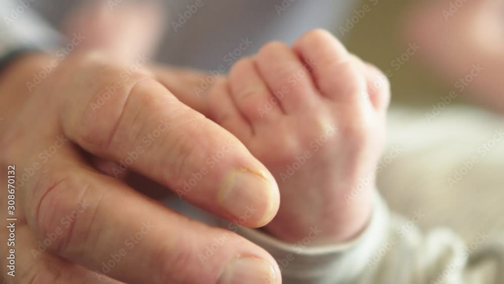 tiny little baby hand squeezing the thumb of the grandpa. Family bonding and love between generations tiny little baby hand squeezing the thumb of the grandpa. Family bonding and love between generations