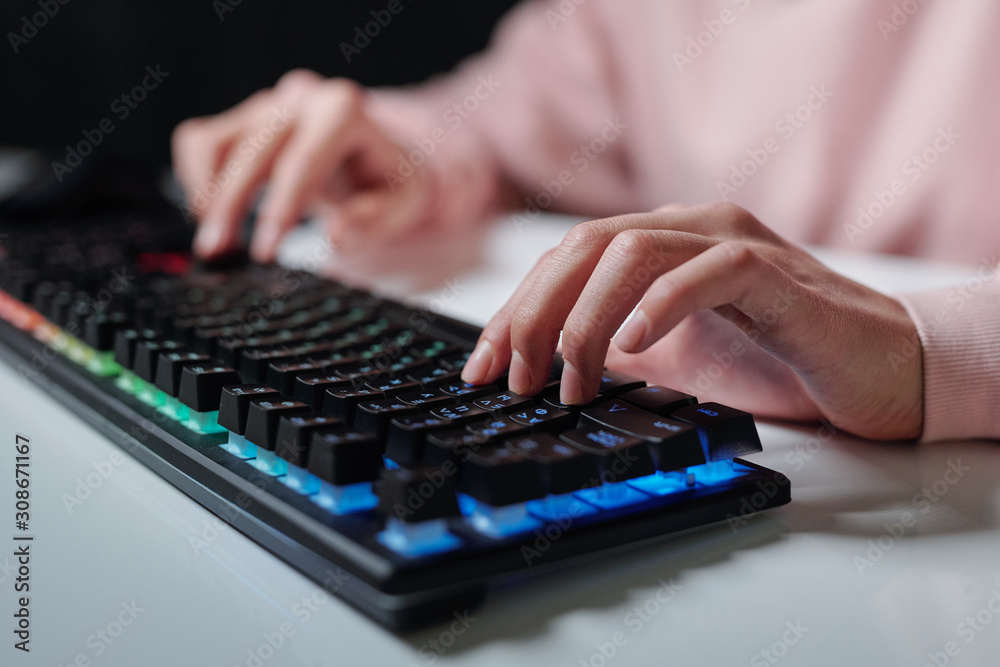 Hands of teenager over keys of computer keyboard typing while sitting by desk Hands of teenager over keys of computer keyboard typing while sitting by desk