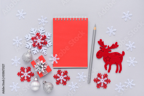 Christmas or New Year greeting card. The notebook with the pencil and christmas decorations on gray background. Flat lay, top view, copy space