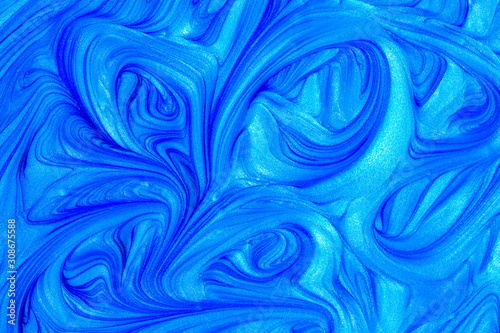 Close up liquid luxury blue metallic glitter paint swirls to make an abstract textured background