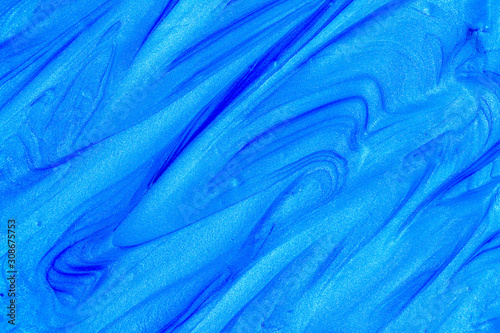 Close up liquid luxury blue metallic glitter paint swirls to make an abstract textured background
