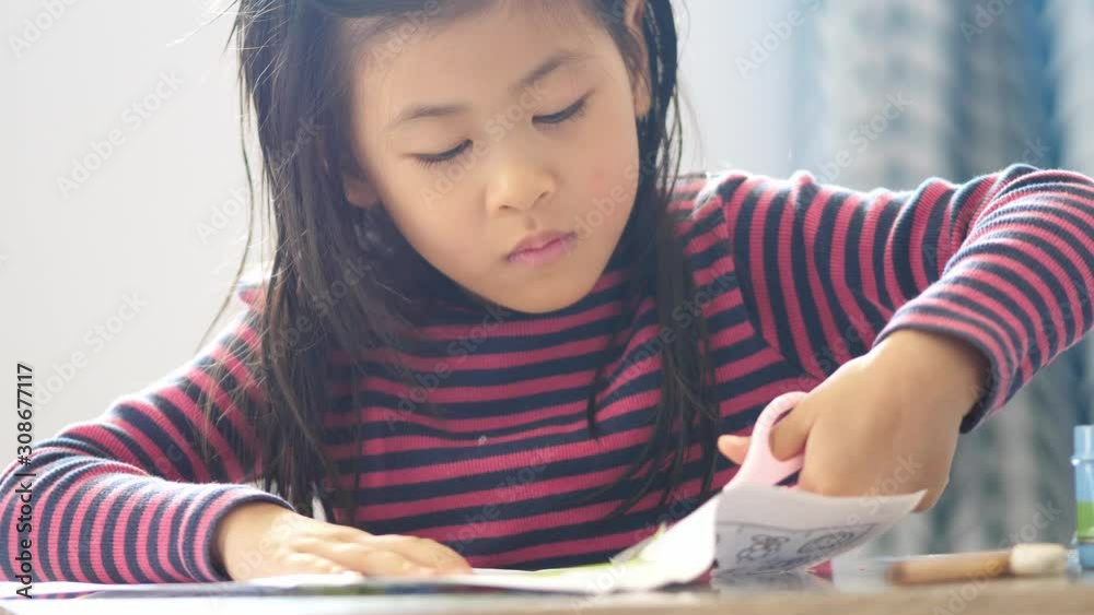 cute asian girl using scissors to cut paper and do homework on winter season, education concept. cute asian girl using scissors to cut paper and do homework on winter season, education concept.