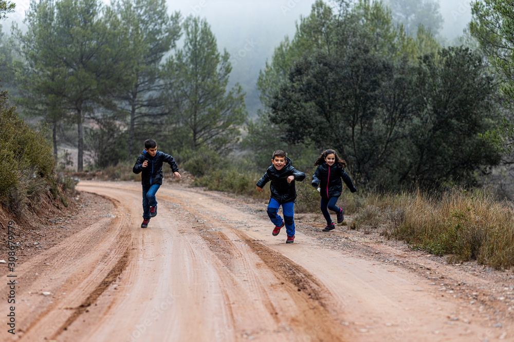 Three kids running on a foggy road