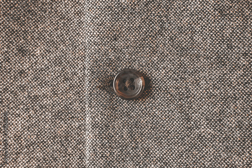 Plain brown button on a thick seamless fabric material background.