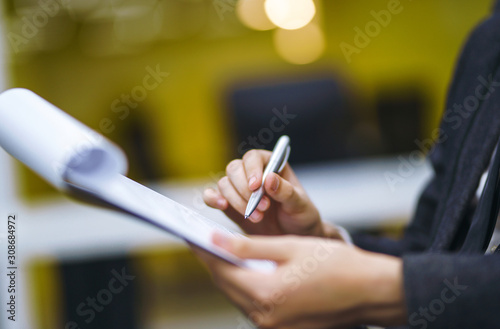 A man signs a contrac, legal or business agreements. Male hand with pen of young office worker makes notes. Business man sitting at office desk and signing a document in modern office.
