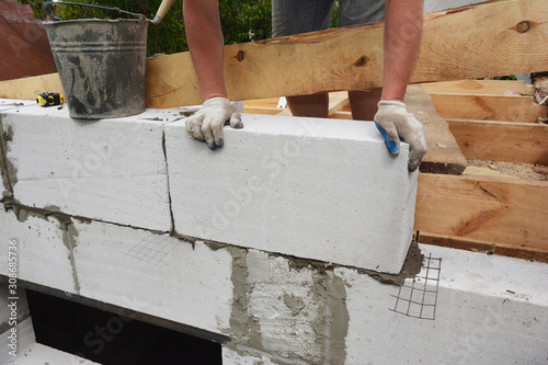 Bricklayer builder laying autoclaved aerated concrete blocks, aac for new house wall. photo