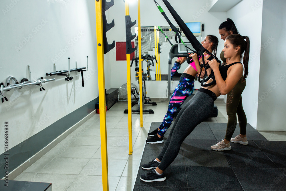 Fototapeta premium Young girls training with suspension gear