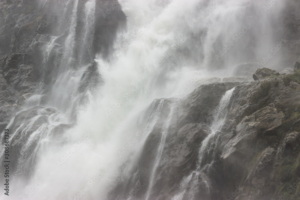 a huge stream of water falls on the rocks from a waterfall, throwing splashes of water