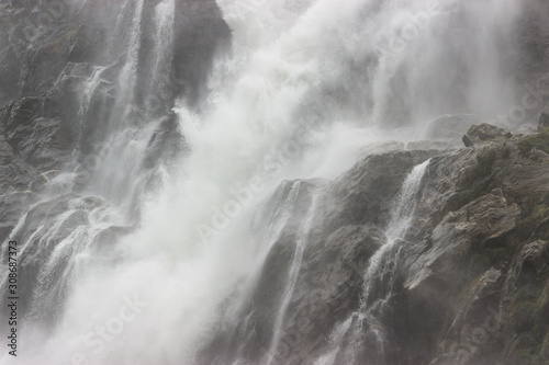 Fototapeta Naklejka Na Ścianę i Meble -  a huge stream of water falls on the rocks from a waterfall, throwing splashes of water