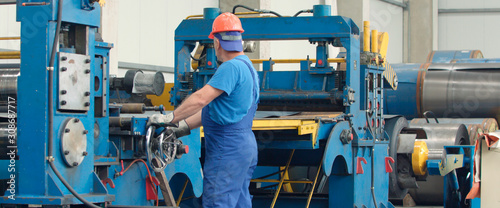Engineer checking and controlling automatic machine in mechanical workshop