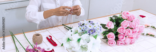 young women business owner florist making or Arranging Artificial flowers vest in her shop  craft and hand made concept