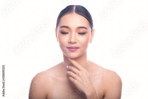 Beautiful Young Asian Woman with Clean Fresh Skin isolate on white background. Spa, Face care, Facial treatment, Beauty and Cosmetics concept. Left hand touch chin, eye close, small smile.