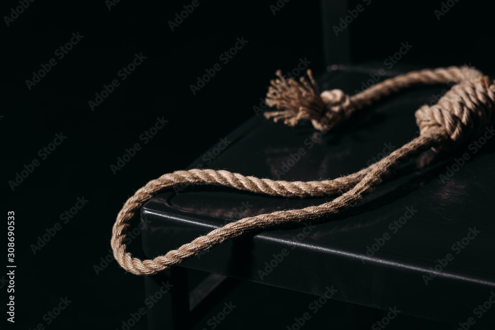 Fototapeta premium rope noose on chair on black background, suicide prevention concept