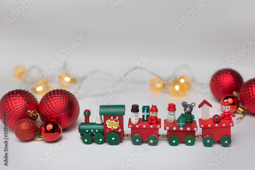 Toy train on a white background with red balls and a shiny garland
