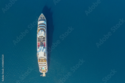 Top down aerial image large holiday cruise ship in the middle of the ocean with the small speed boat across around. © muslian