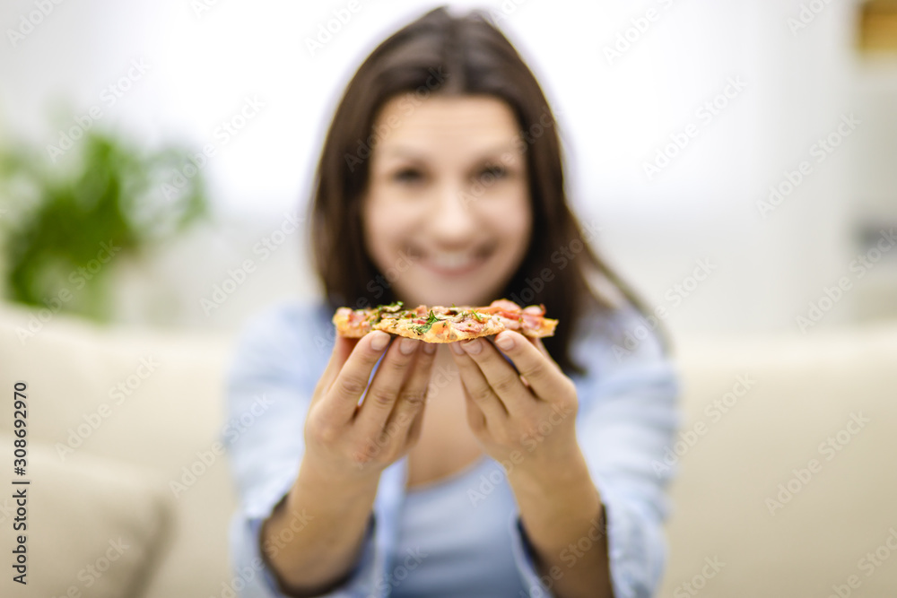 Blurred smiling woman is presenting hot, delicious slice of pizza. Close up. Copy space.