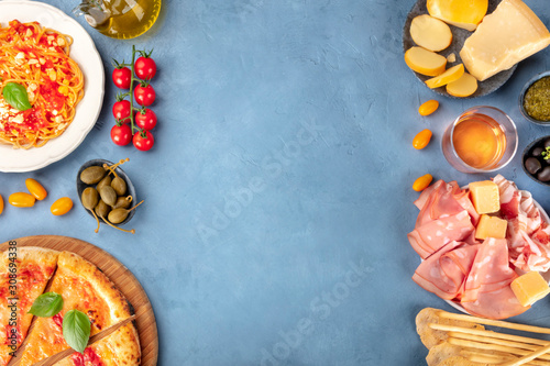 Italian food. Pizza, pasta, cheese, hams, wine and capers, shot from above with a place for text, a flat lay composition